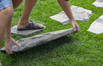 the gardener mounts a step by step path from natural stone to the lawn